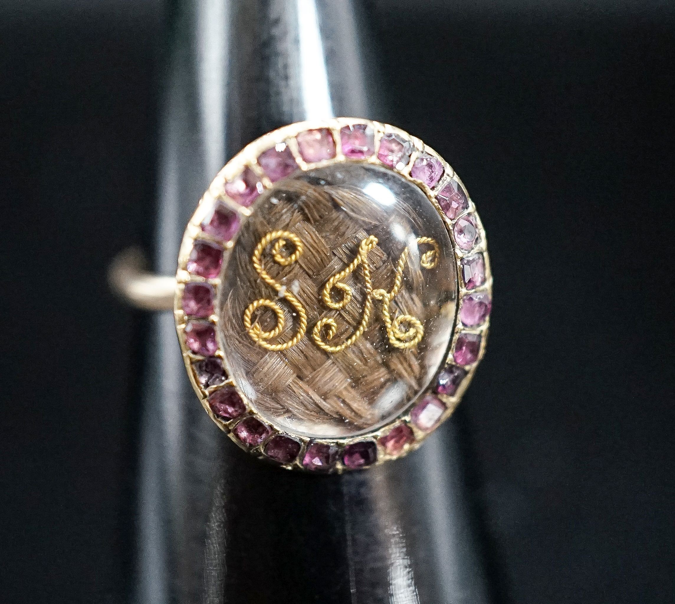 A 19th century yellow metal and gem set mounted glazed mourning ring, with 'S.H.' initialled above plaited hair, size I, gross weight 2.9 grams (adapted).